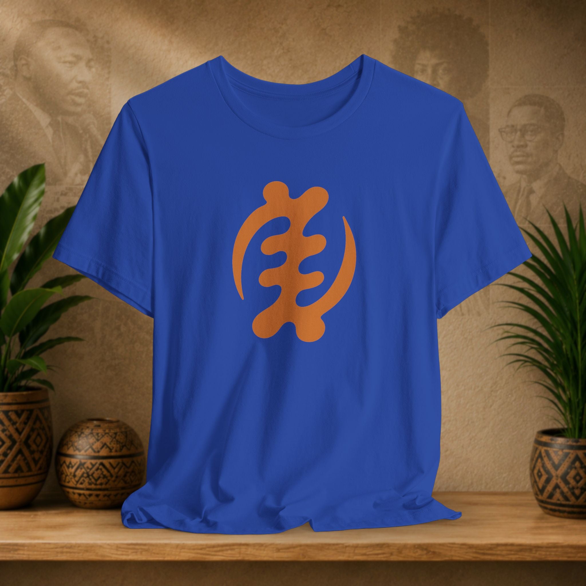 Blue t-shirt with orange symbol on a wooden surface with plants and decorative items in the background