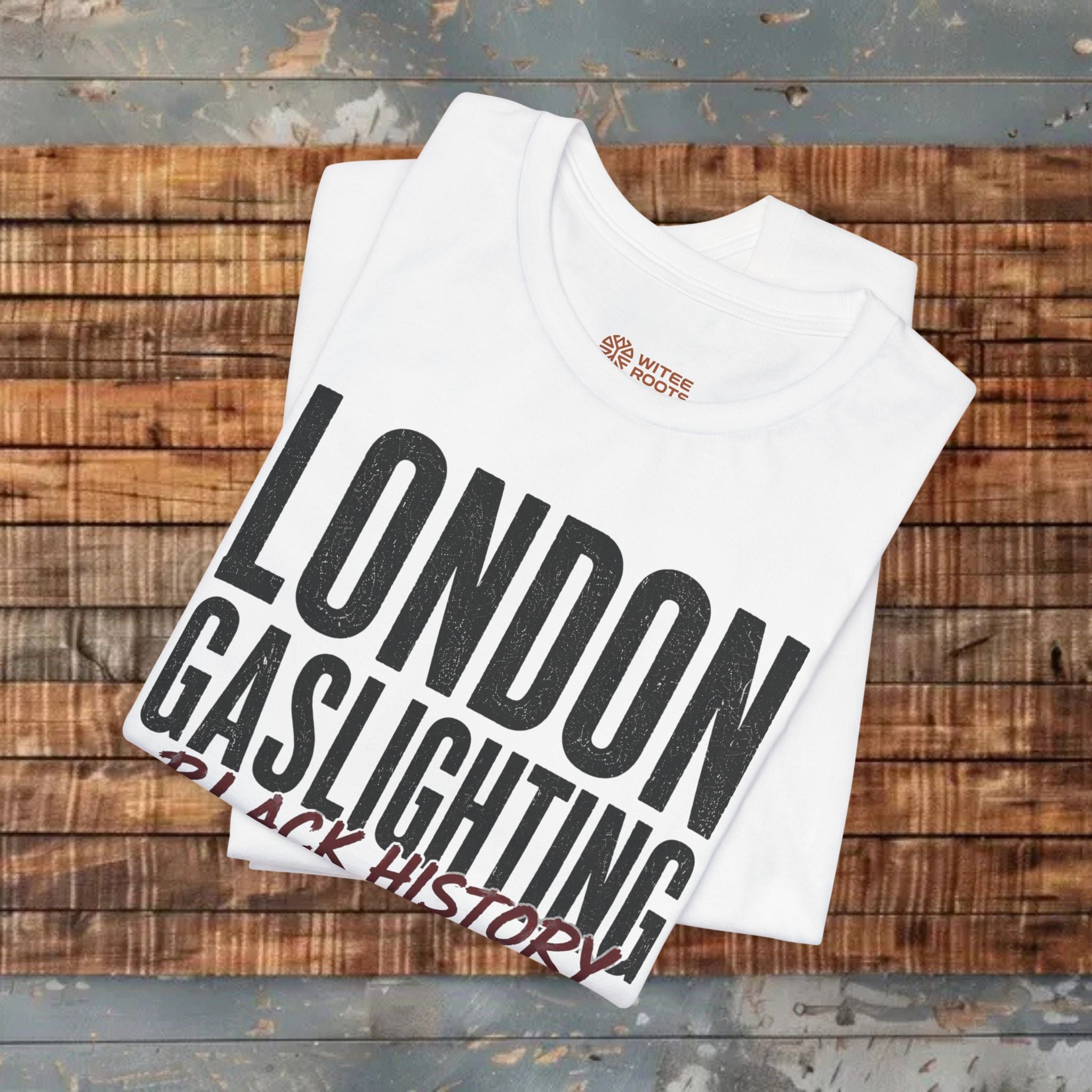 White t-shirt with 'London Gaslighting Black History' text on a wooden surface