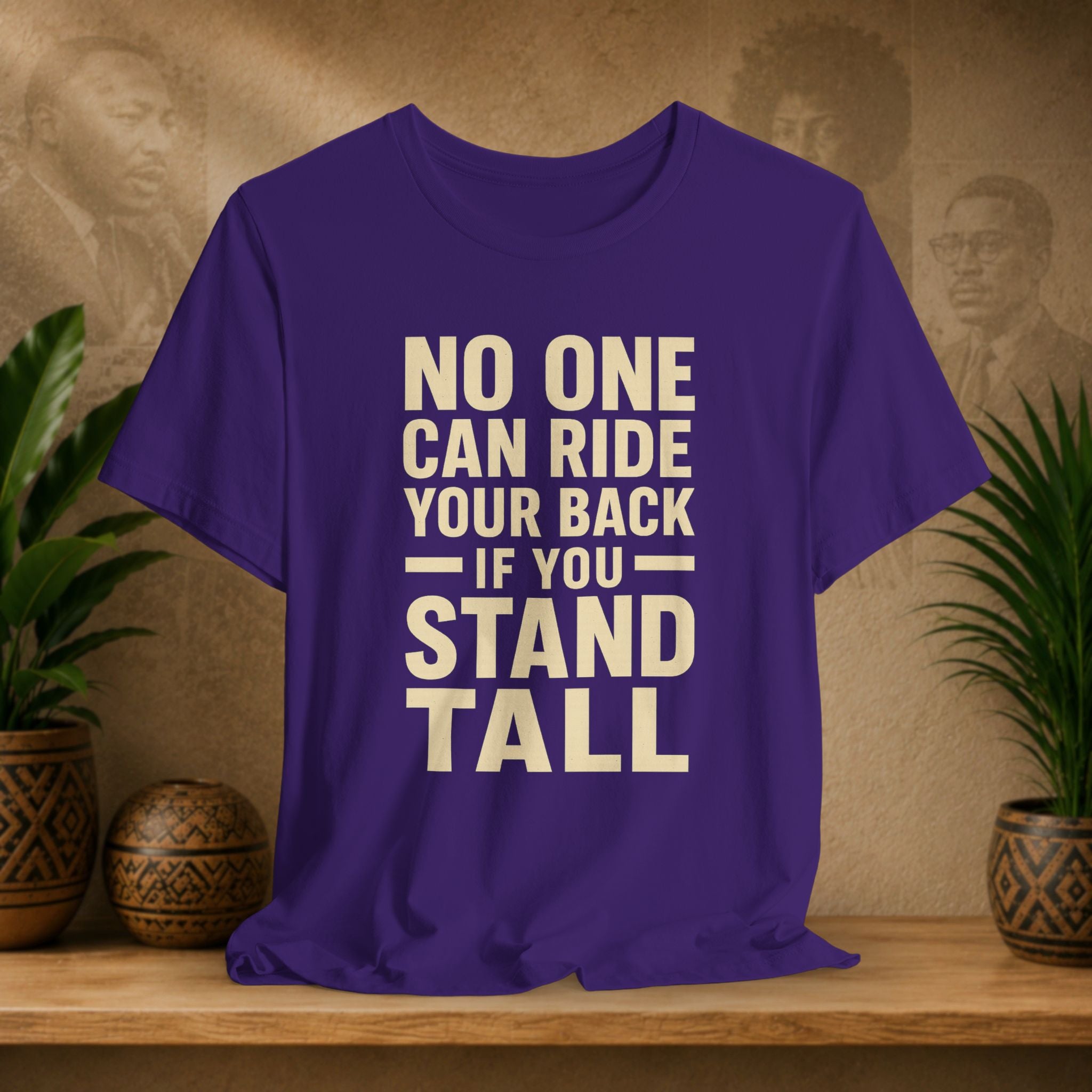 Purple t-shirt with motivational quote on a wooden surface with decorative plants and background.