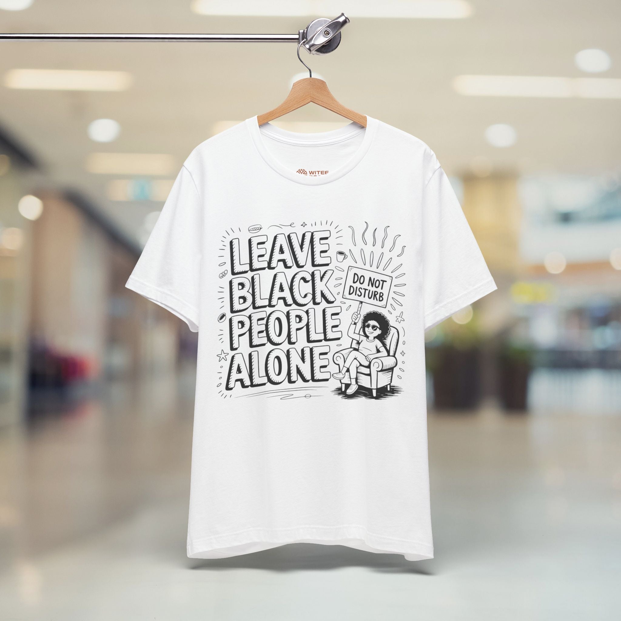 White t-shirt with black text and graphic on a hanger in a store setting