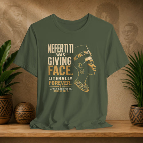 Green t-shirt with a graphic of Nefertiti and text on a wooden surface with plants and decorative items.