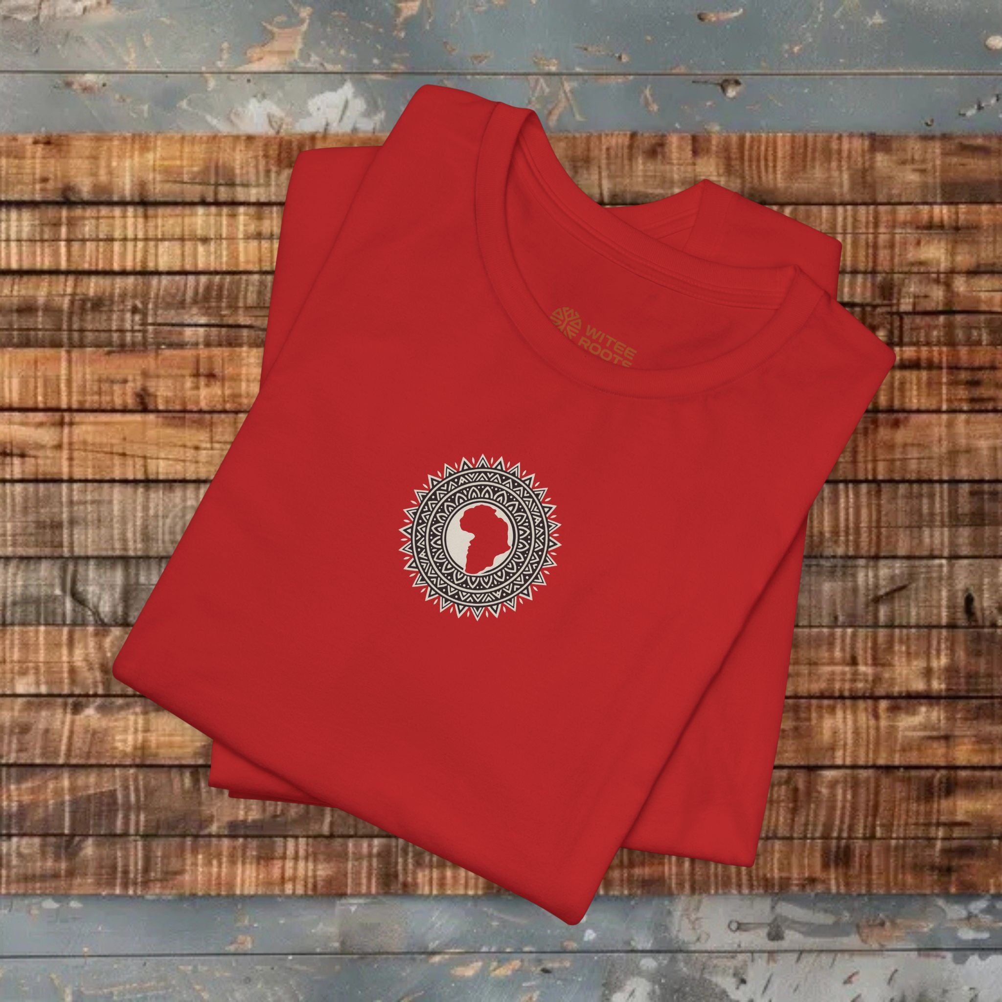 Folded red t-shirt with a circular design on a wooden surface