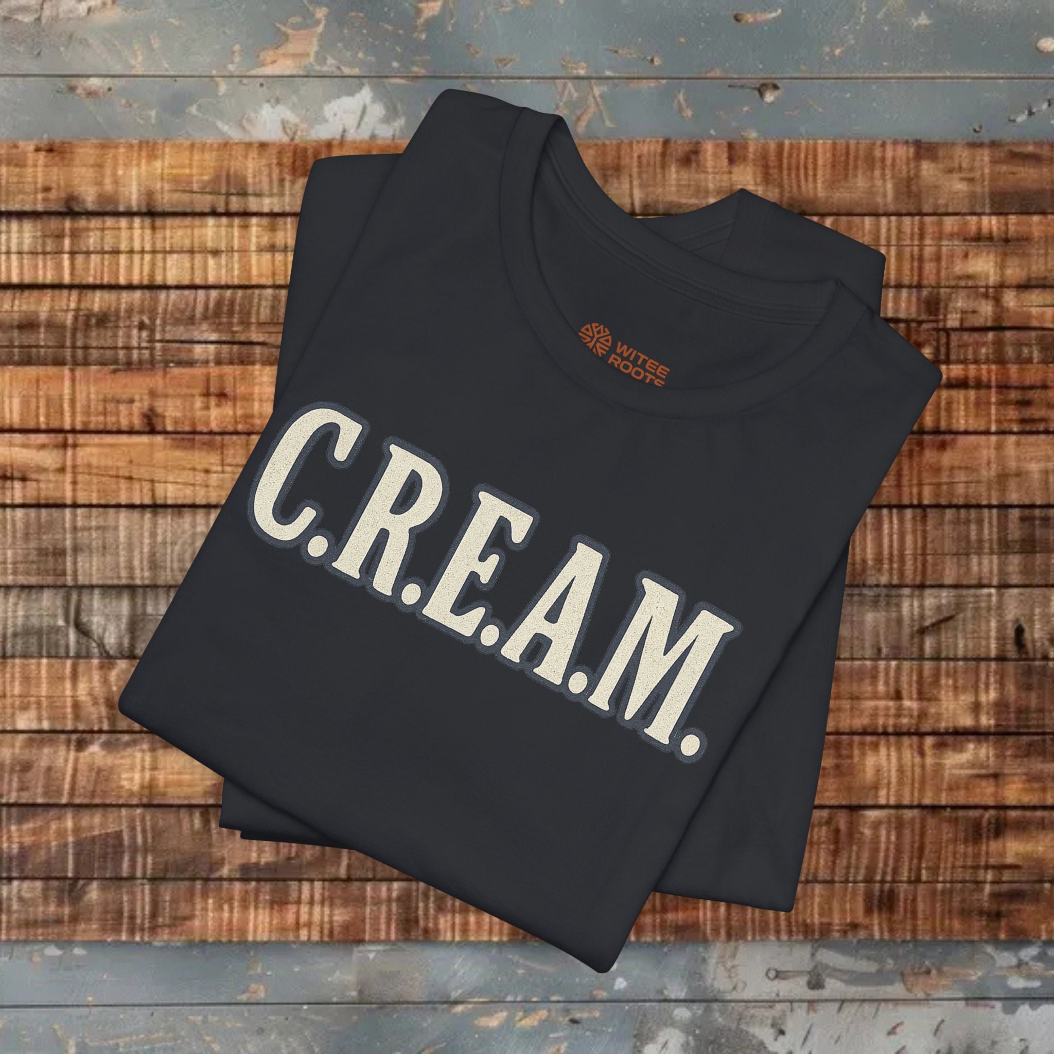 Black sweatshirt with 'C.R.E.A.M.' text on a wooden surface