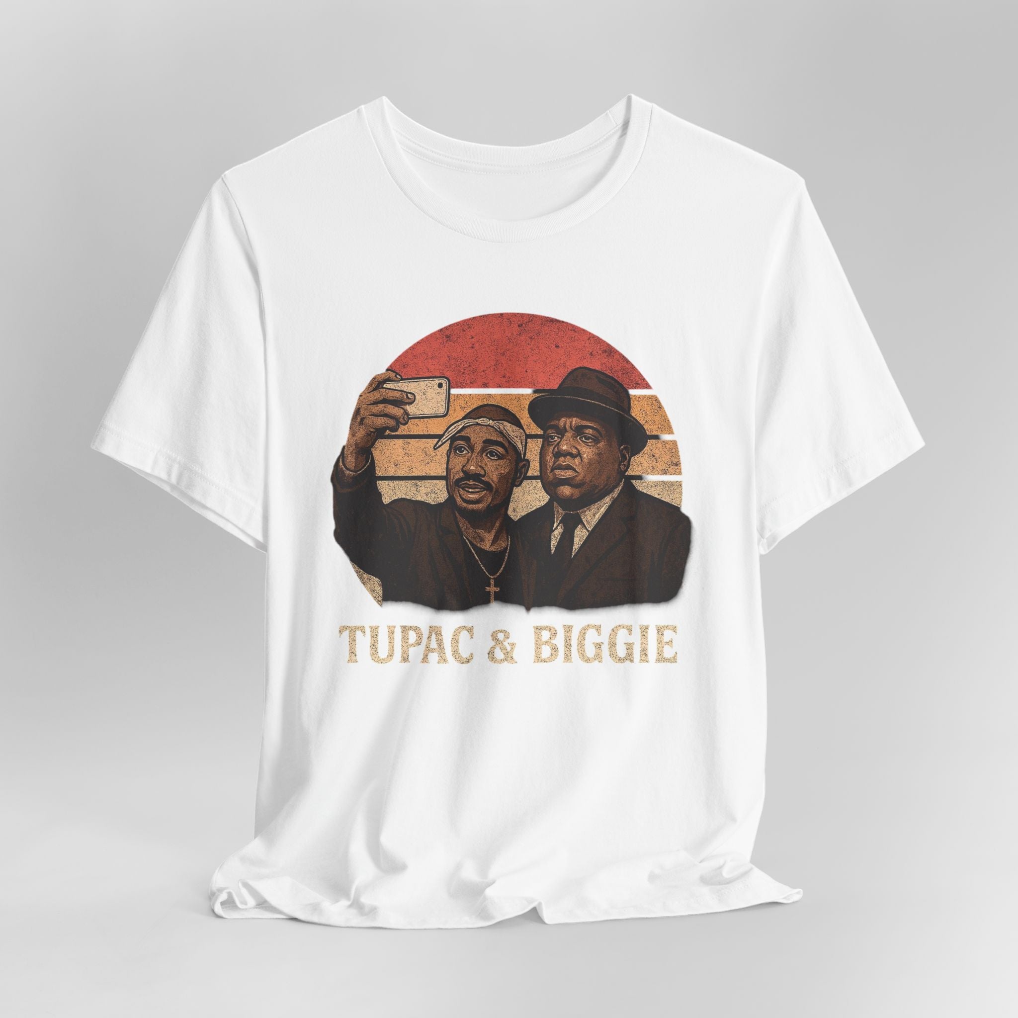 White t-shirt with graphic of two men taking a selfie and 'Tupac & Biggie' text on a gray background