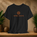 Black t-shirt with 'WITEE ROOTS' logo on a wooden surface with decorative items and plants.