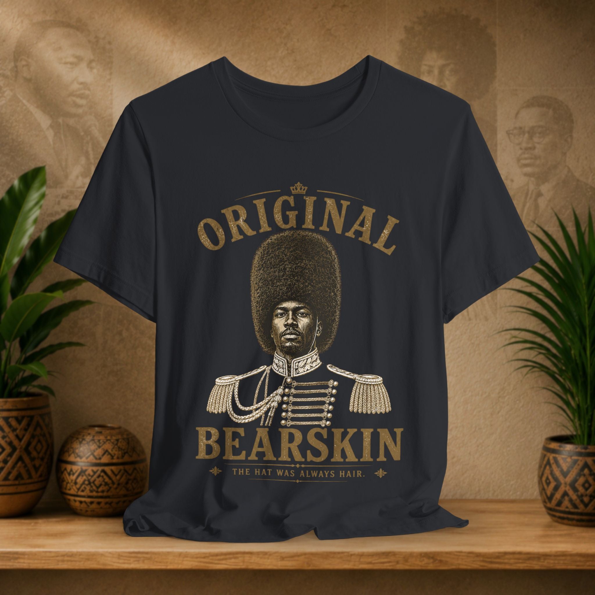 Black t-shirt with a graphic of a man with an afro and text 'Original Bearskin' on a wooden surface with plants and a decorative wall.