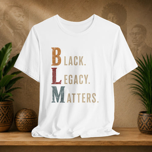 A white short-sleeve T-shirt displayed on a wooden surface, featuring a vertical graphic that reads 'BLACK. LEGACY.