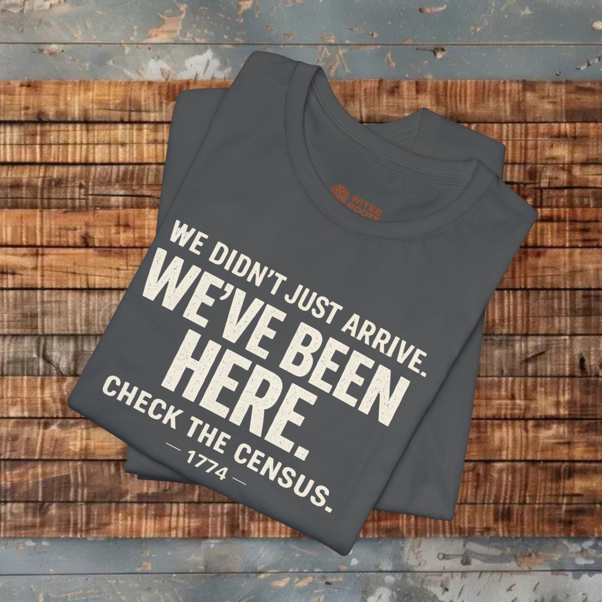 Folded gray t-shirt with humorous text on a wooden surface