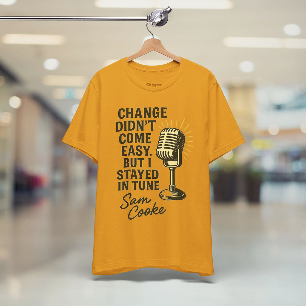 Yellow t-shirt with a microphone graphic and text on a hanger in a store.