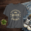 Gray t-shirt with 'Easily Distracted by Queen Energy' text on a wooden surface with jeans and sneakers.