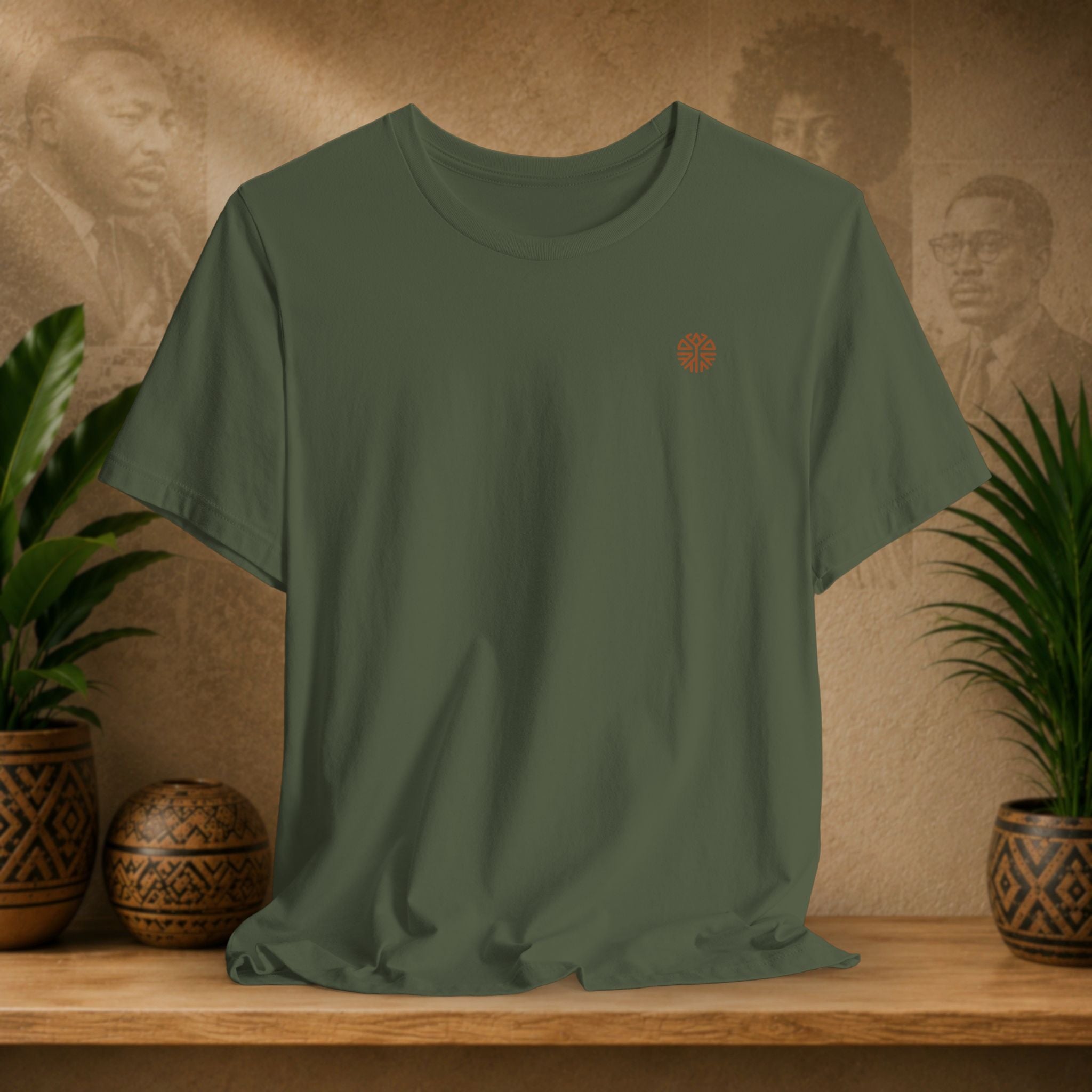 Green t-shirt with a colorful logo on a wooden surface with plants and a textured wall background