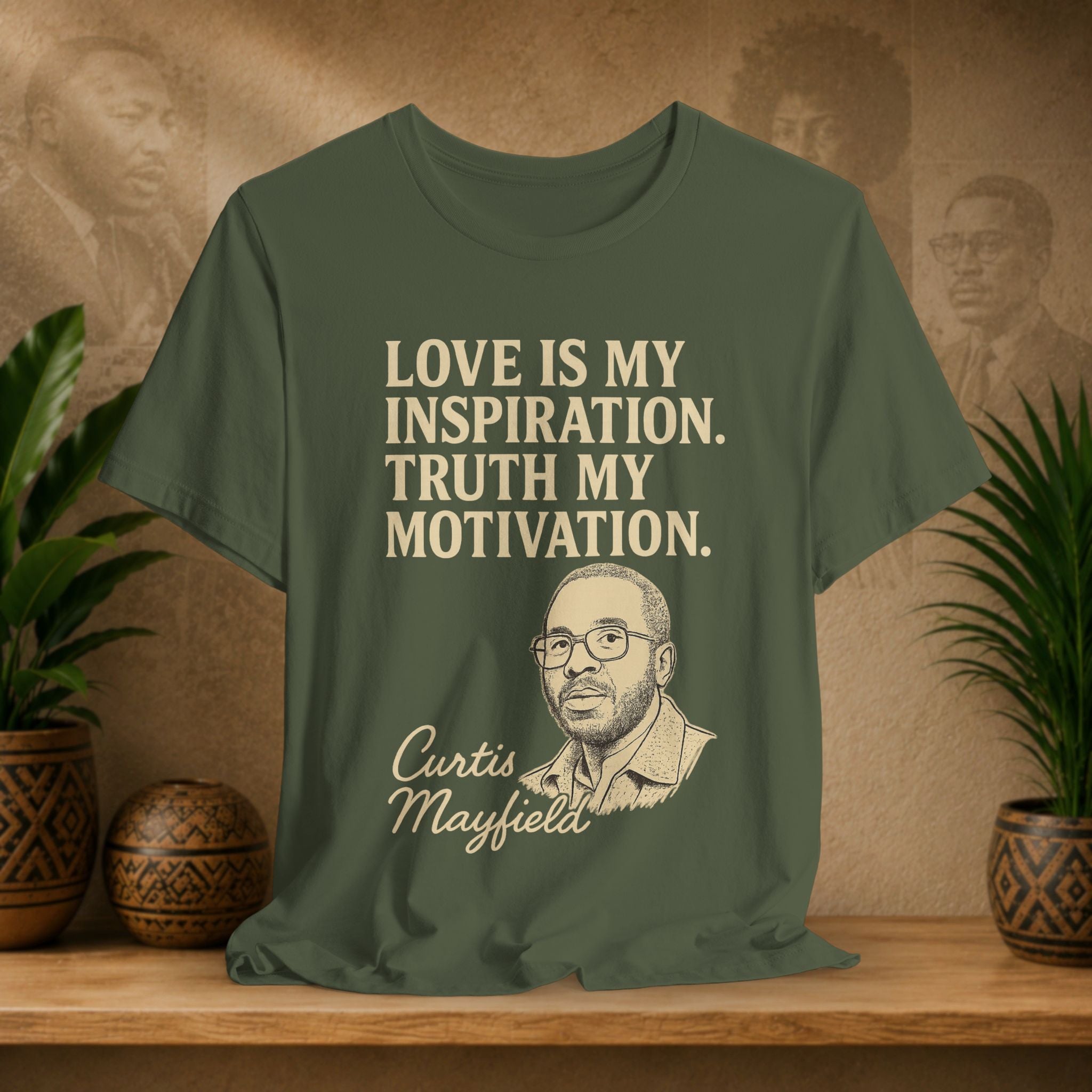 Green t-shirt with text and a portrait of Curtis Mayfield on a wooden surface with plants and a wall with portraits in the background.