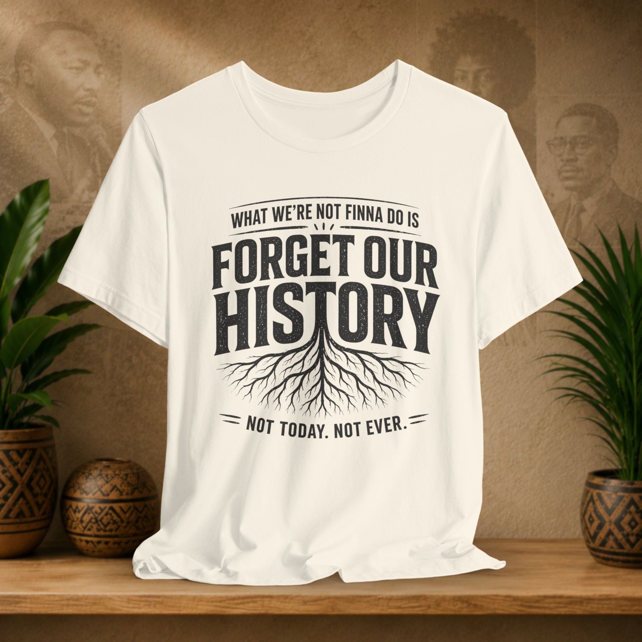 Beige t-shirt with 'Forget Our History' text on a wooden shelf with plants and a textured wall background