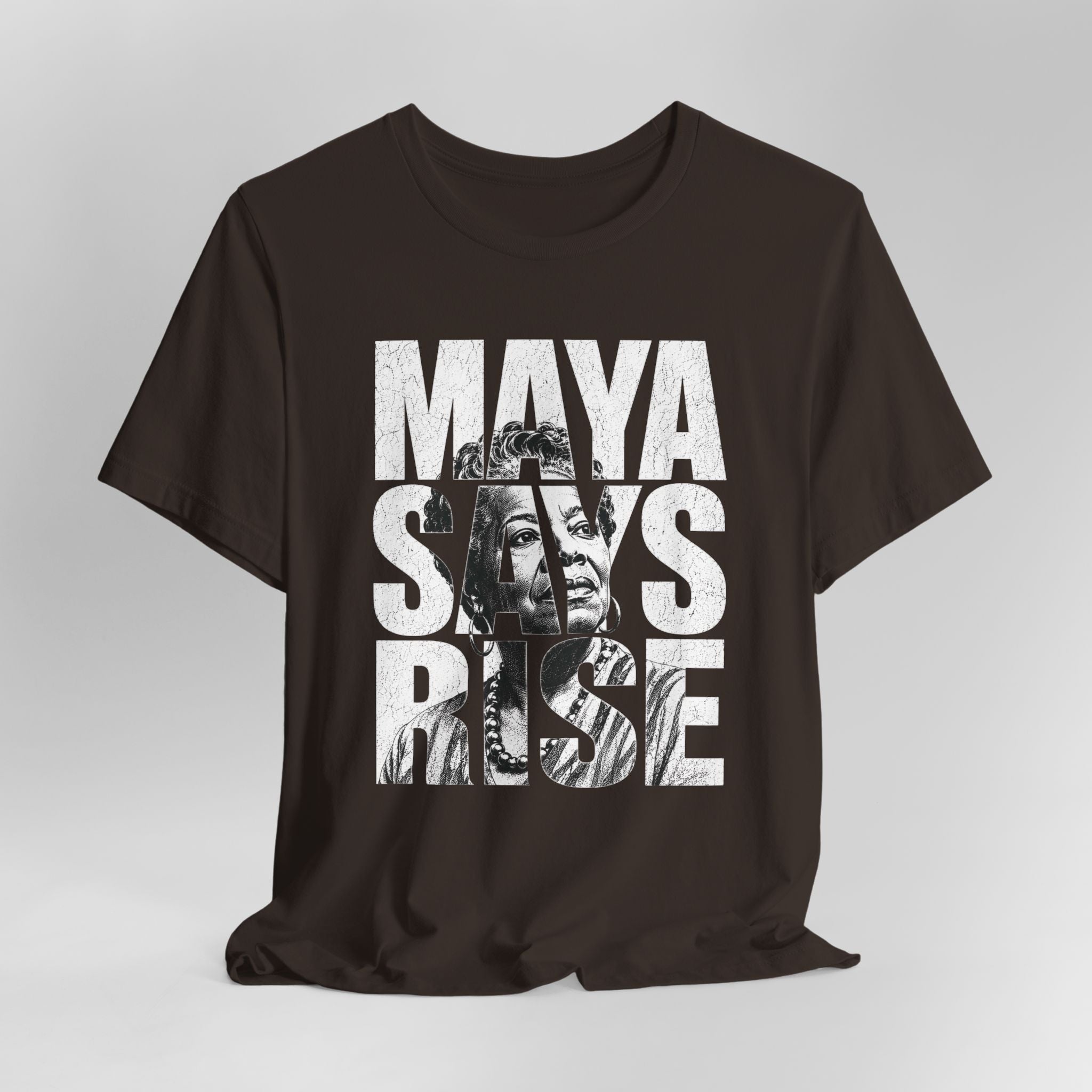 Brown t-shirt with 'MAYA SAYS RISE' text and graphic on a gray background