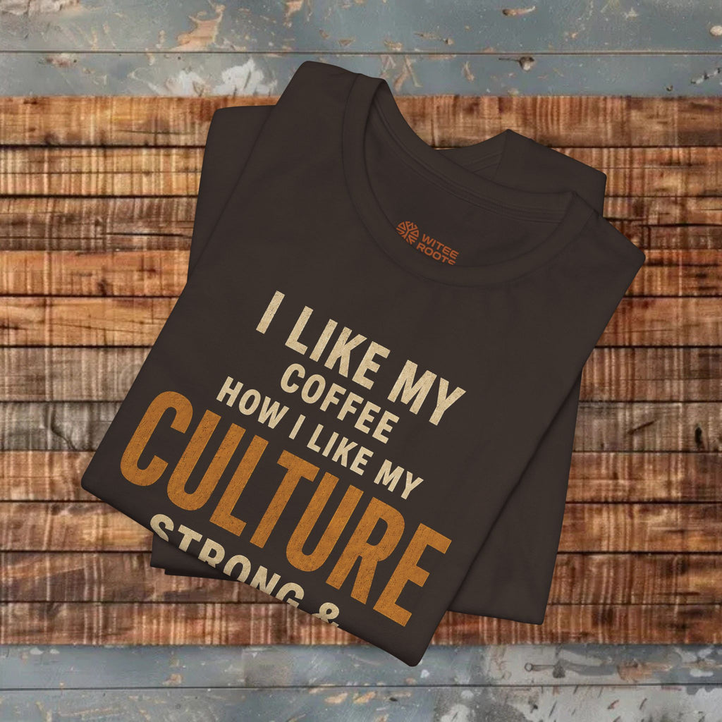 A folded dark brown t-shirt with a humorous coffee-themed graphic print, displayed on a rustic wooden plank surface.