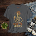 Gray t-shirt with skeleton design and 'BOO-TEE-LICIOUS' text on a wooden surface with jeans and sneakers.