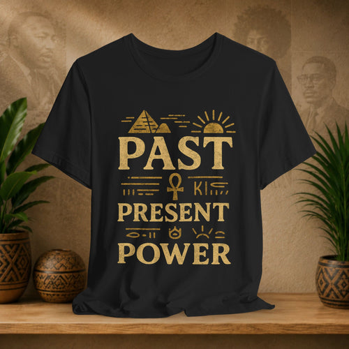 Black t-shirt with gold text and symbols on a wooden surface with plants and decorative items.