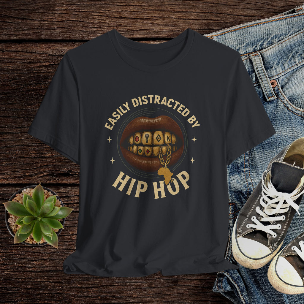 Black t-shirt with 'Easily Distracted by Hip Hop' graphic on a wooden surface with jeans and sneakers.