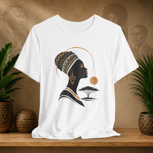 White t-shirt with a black silhouette of a woman with a headscarf and tree design on a wooden surface with plants and decorative items.