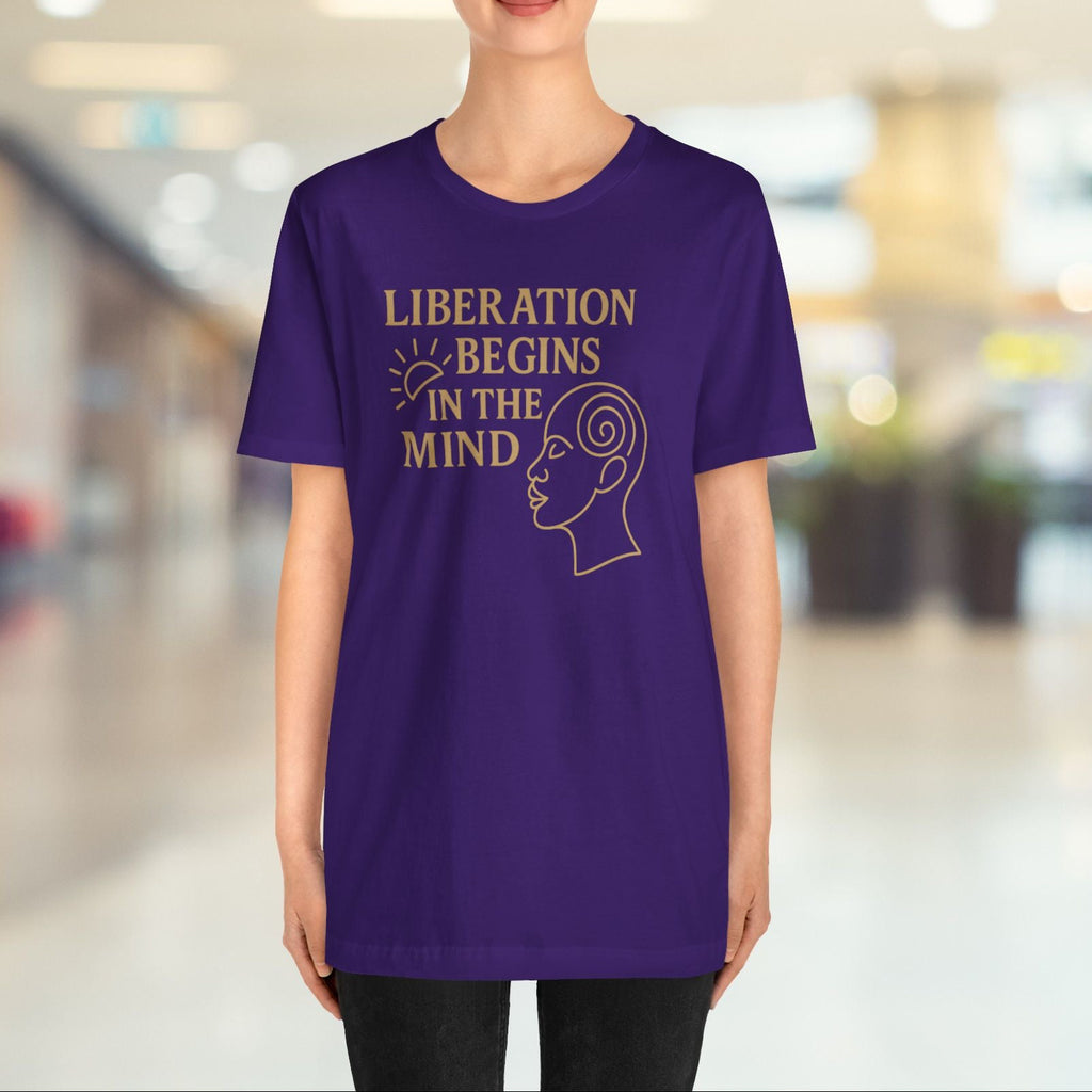 Person wearing a purple t-shirt with text and graphic in a blurred indoor setting