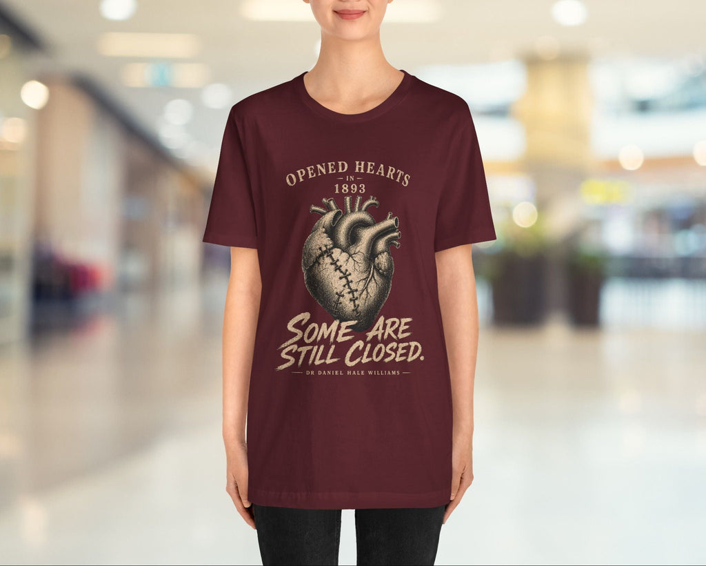 Person wearing a maroon t-shirt with a graphic design and text in an indoor setting