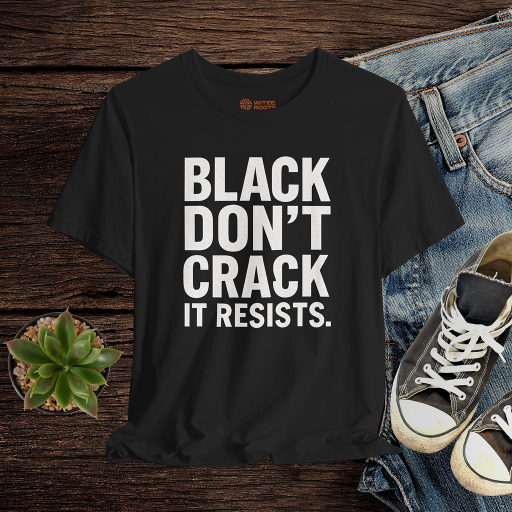 Black t-shirt with text on a wooden surface with jeans and sneakers.