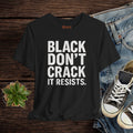 Black t-shirt with text on a wooden surface with jeans and sneakers.