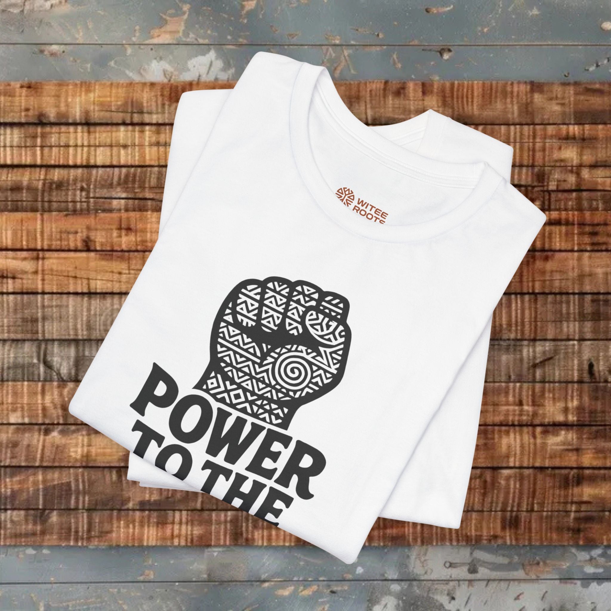 White t-shirt with black graphic and 'Power to the' text on a wooden surface