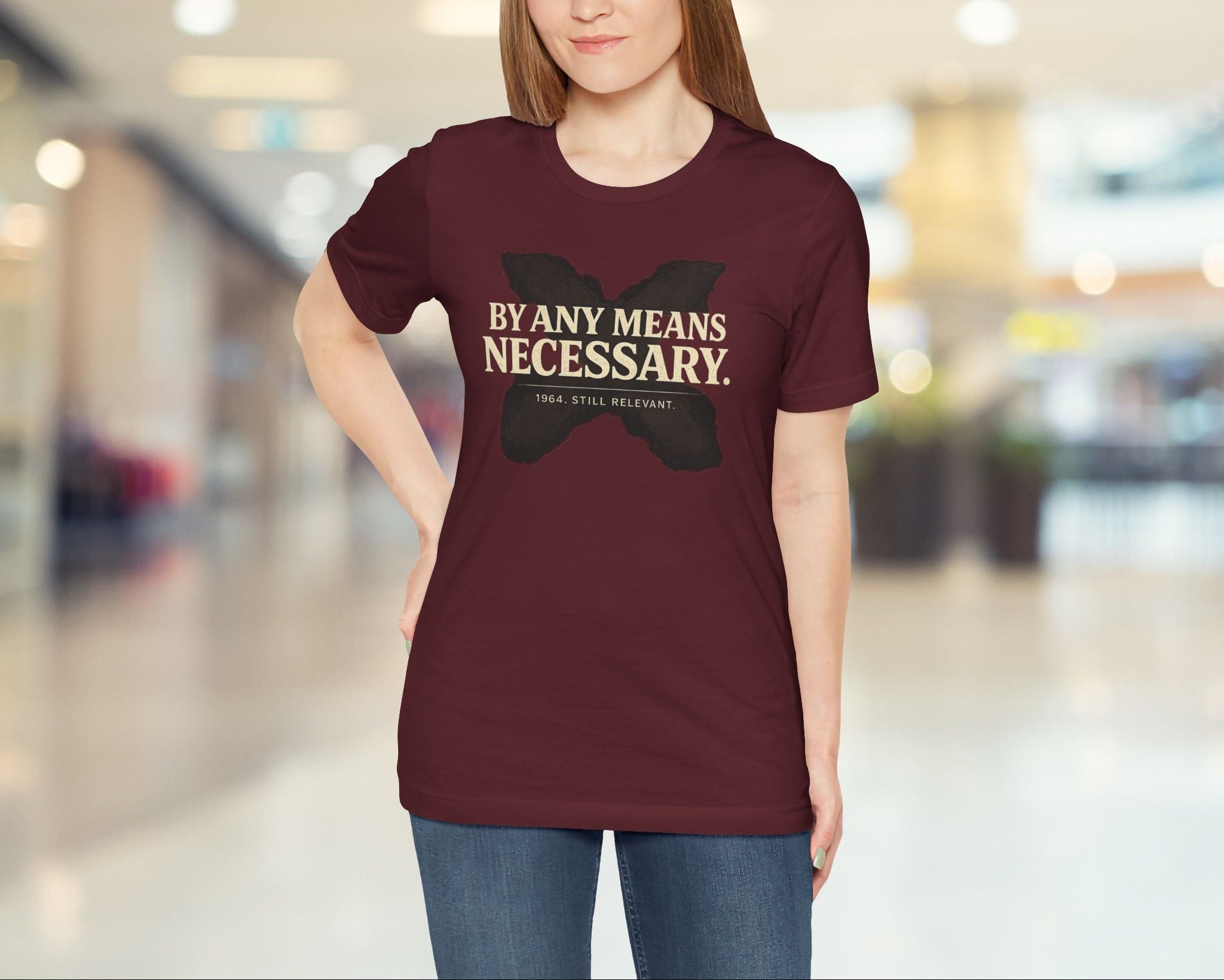 Woman wearing a maroon t-shirt with text in a blurred indoor setting