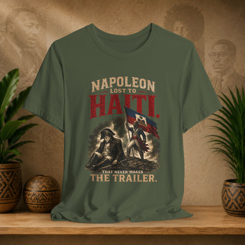 Green t-shirt with historical design and text on a wooden surface with plants and decorative items.