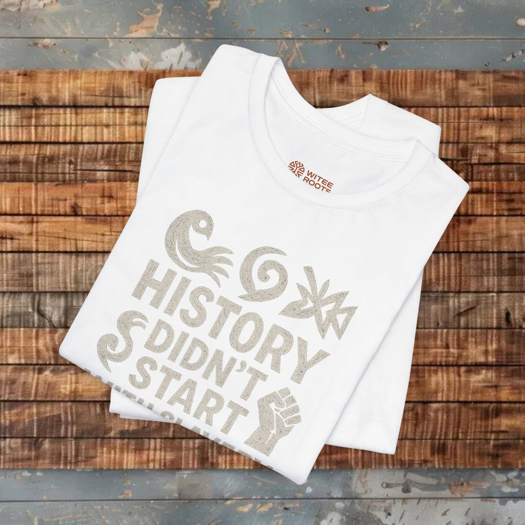 White t-shirt with 'History Didn't Start' design on a wooden surface