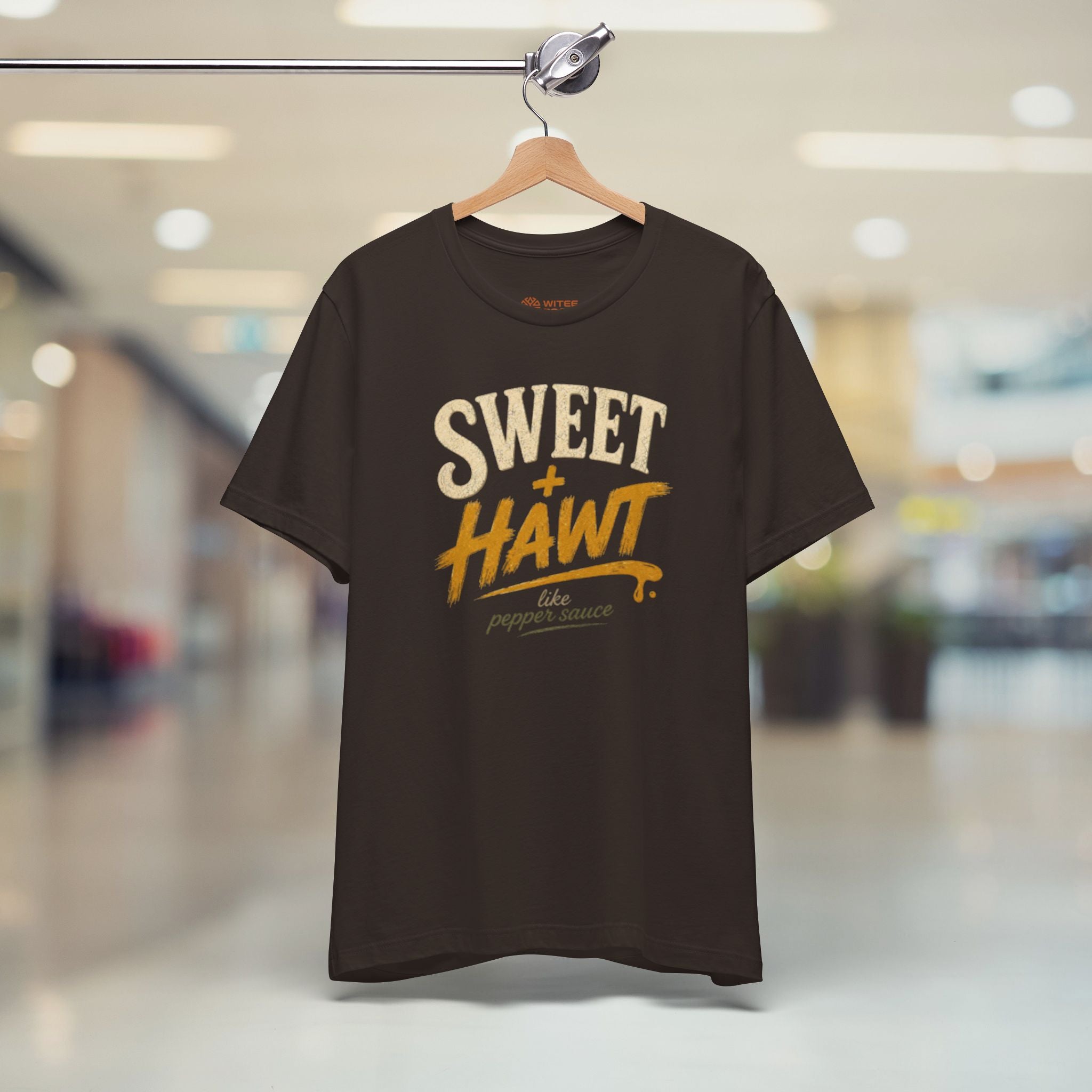 Brown t-shirt with text on a hanger in a store setting