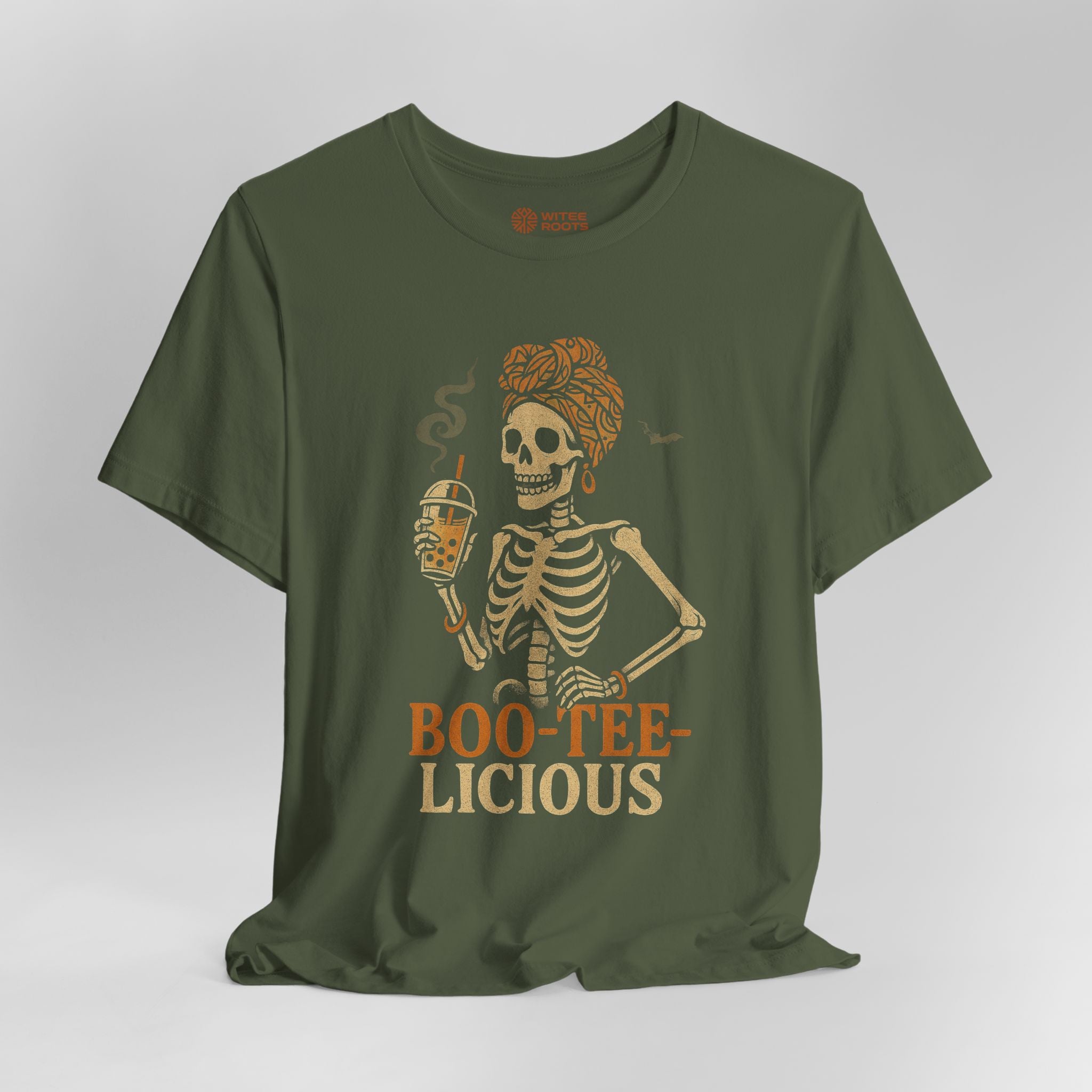 An olive green short-sleeve t-shirt with a graphic of a skeleton holding a beer mug, with the text 'BOO-TEE-LICIOUS' printed below in orange and beige, displayed on a light gray background.
