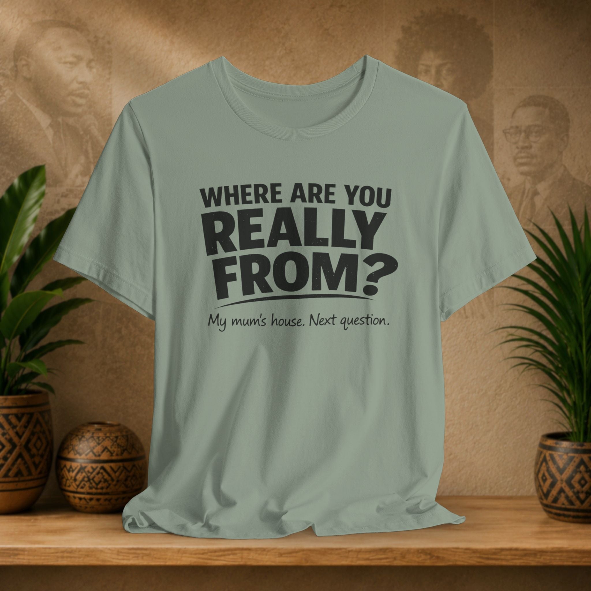 Light green t-shirt with humorous text on a wooden surface with plants and a blurred background