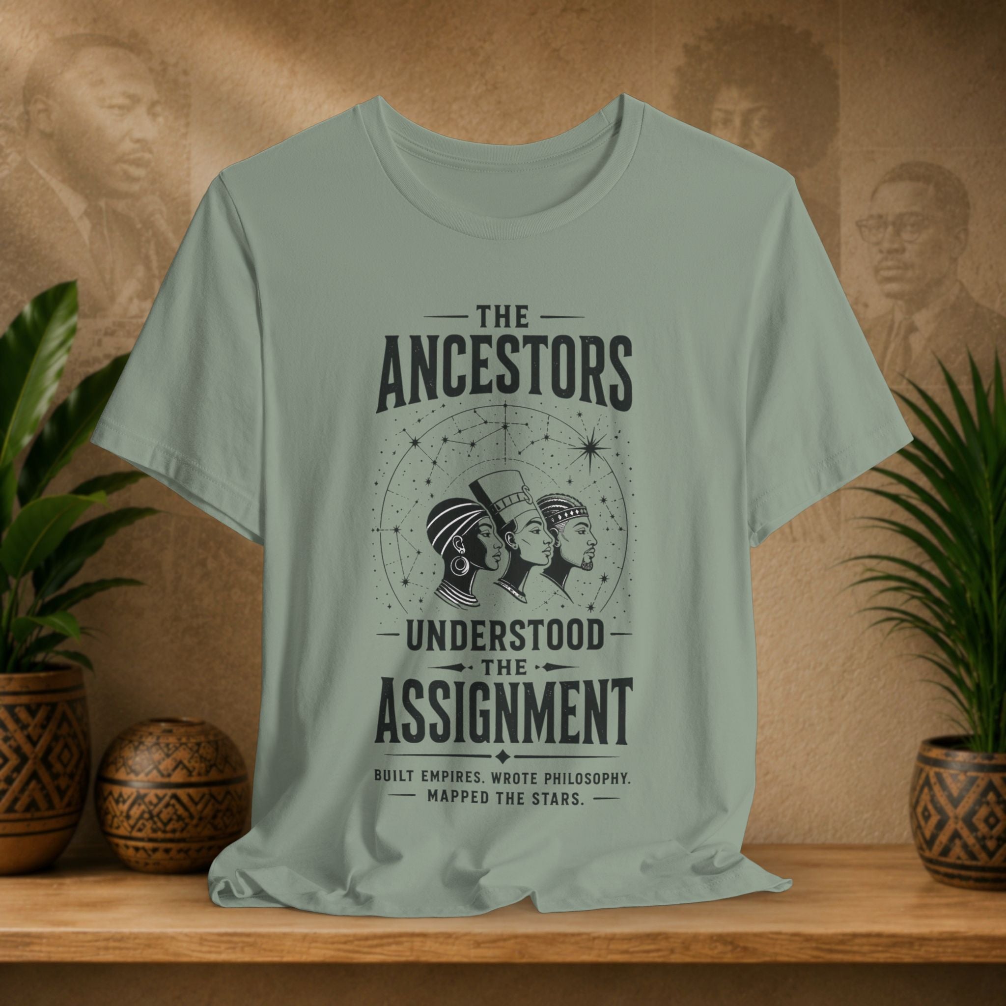 Light green t-shirt with graphic design and text on a wooden surface with decorative items.