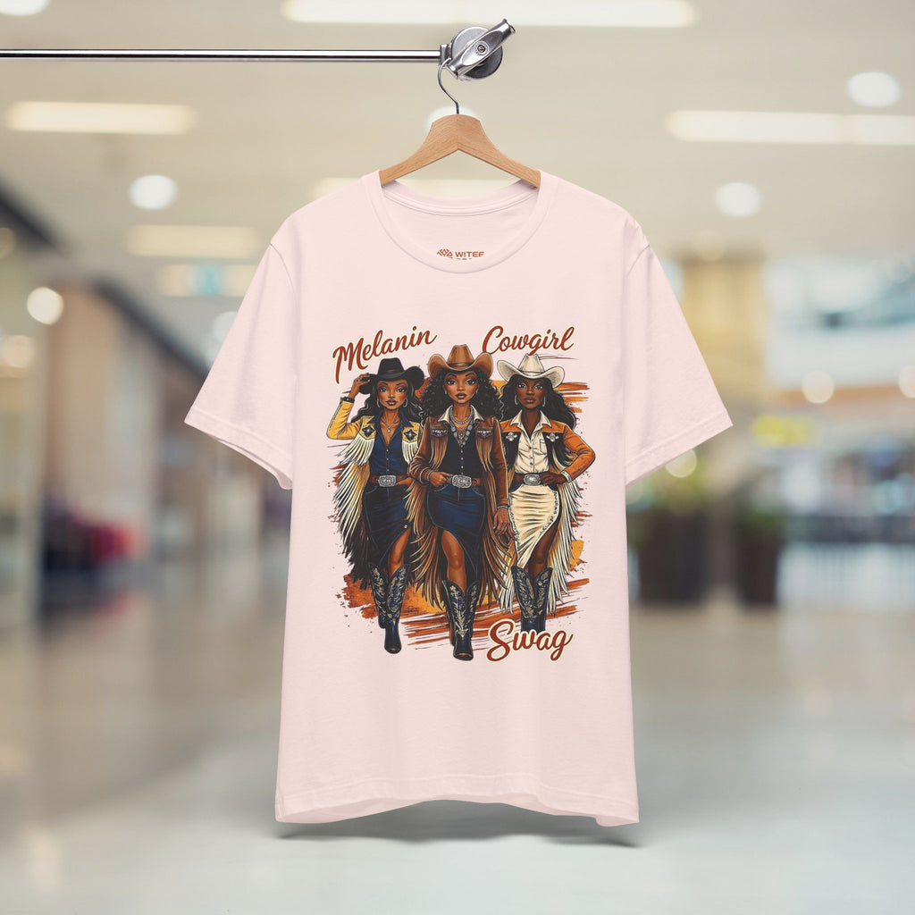 Pink t-shirt with cowgirl graphic and text on a hanger in a store setting