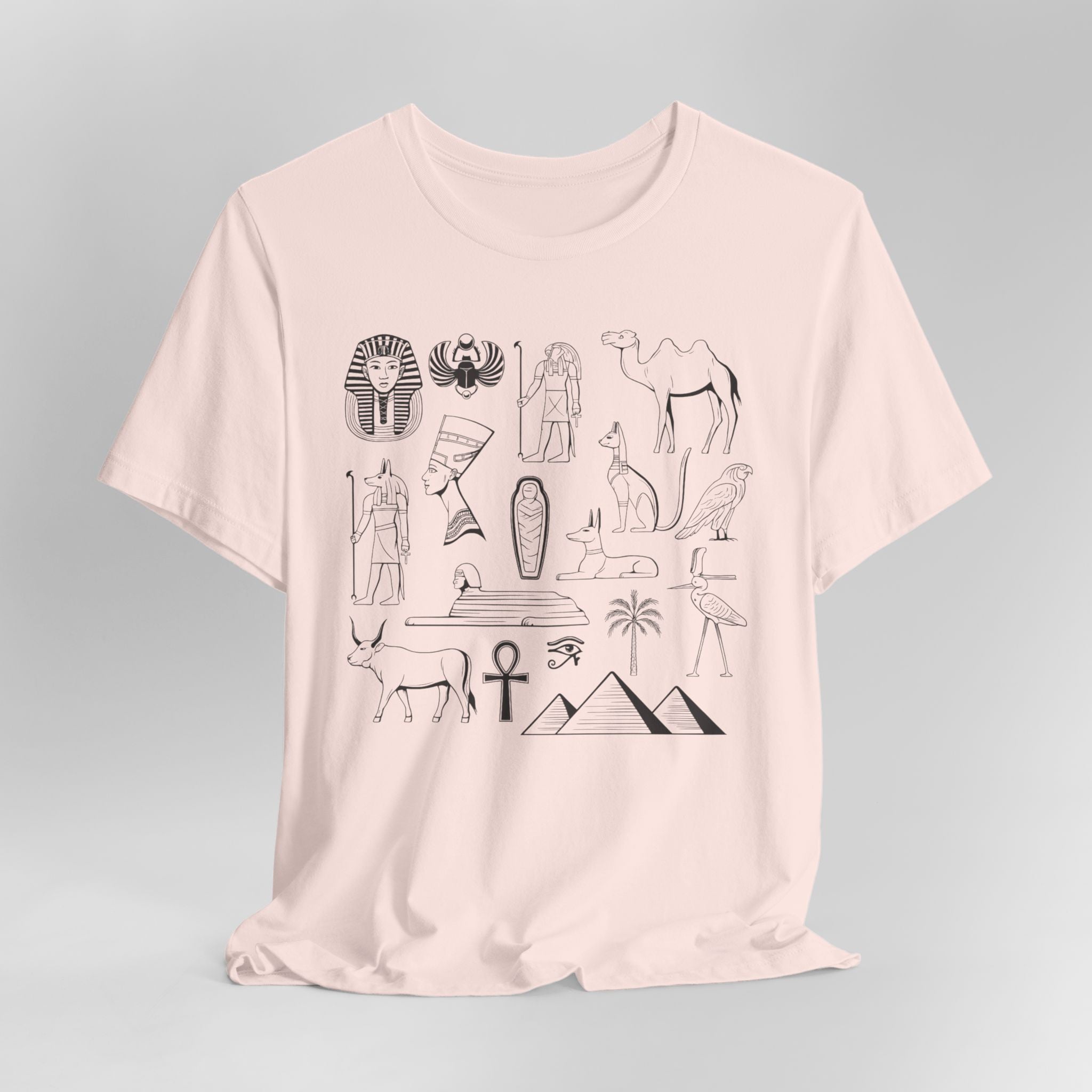 Pink t-shirt with black Egyptian-themed graphics on a gray background