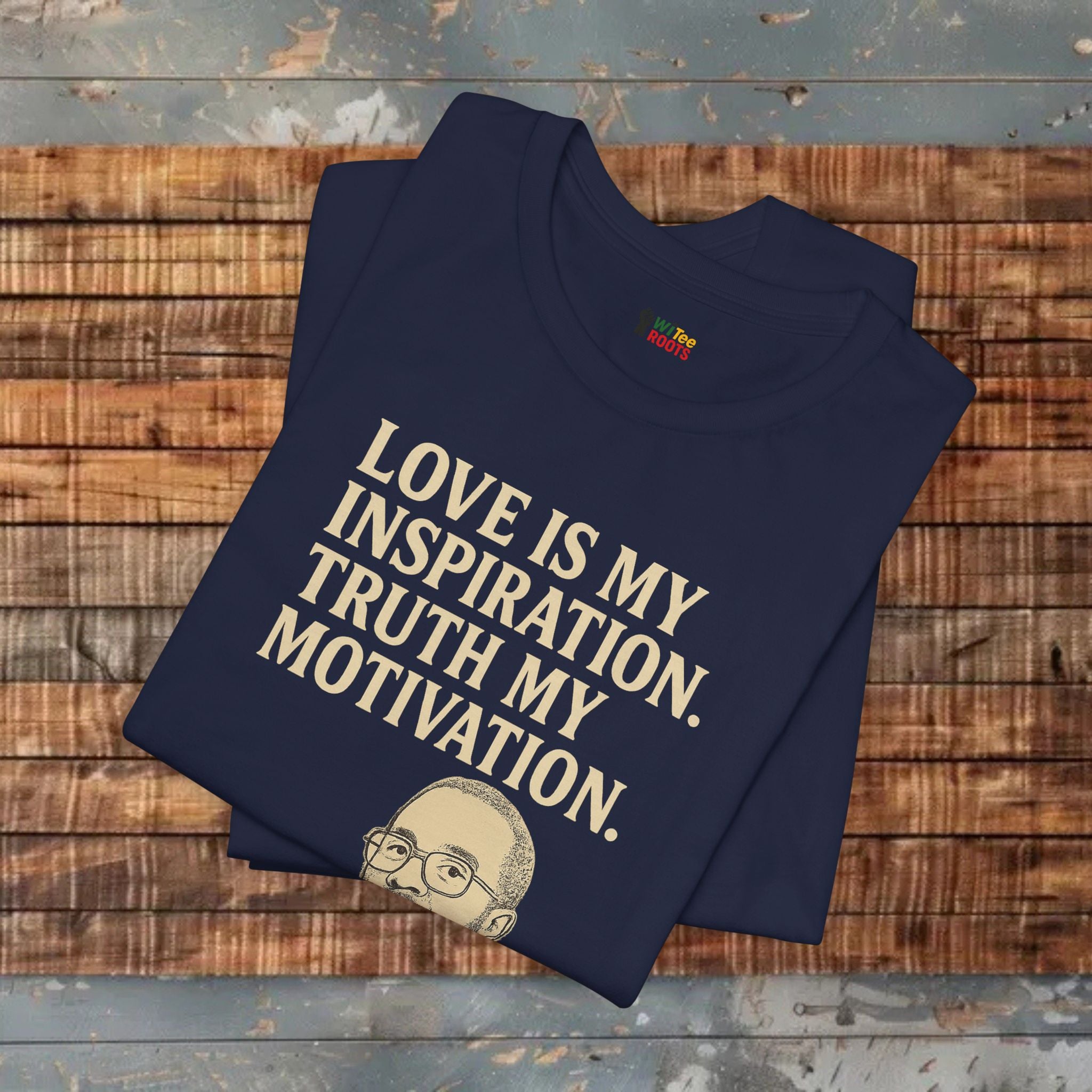 Folded navy blue t-shirt with text and a small graphic on a wooden surface