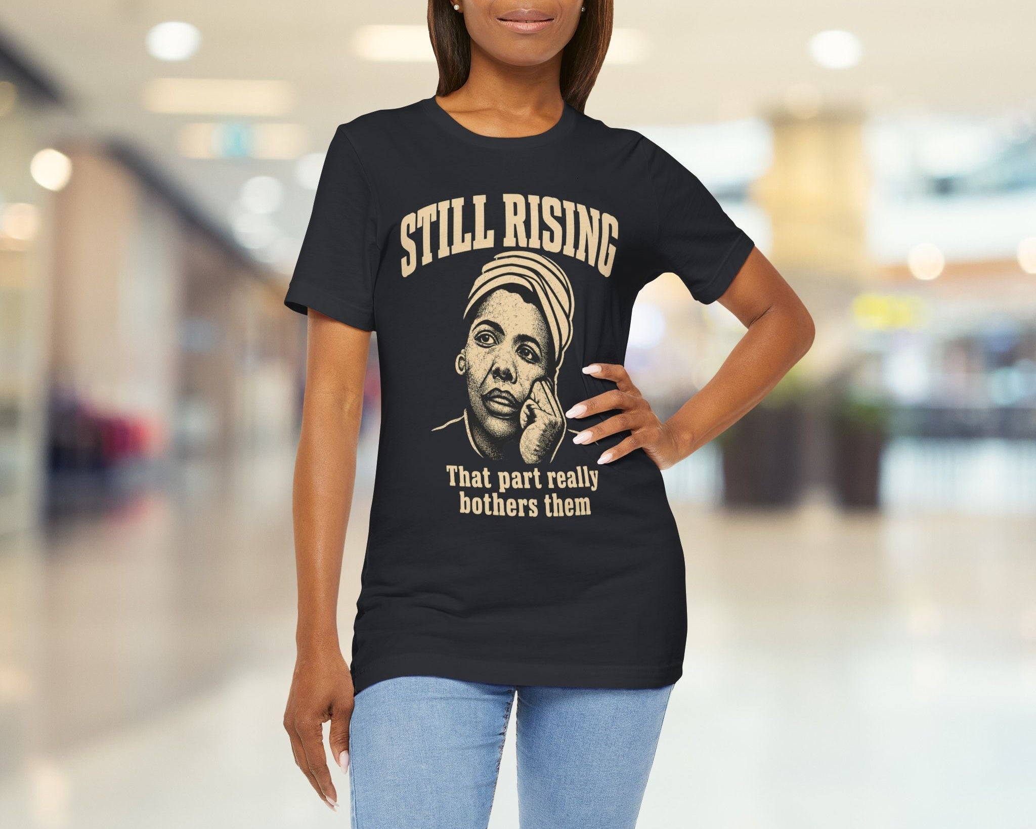 Woman wearing a black t-shirt with a graphic and text in a blurred indoor setting