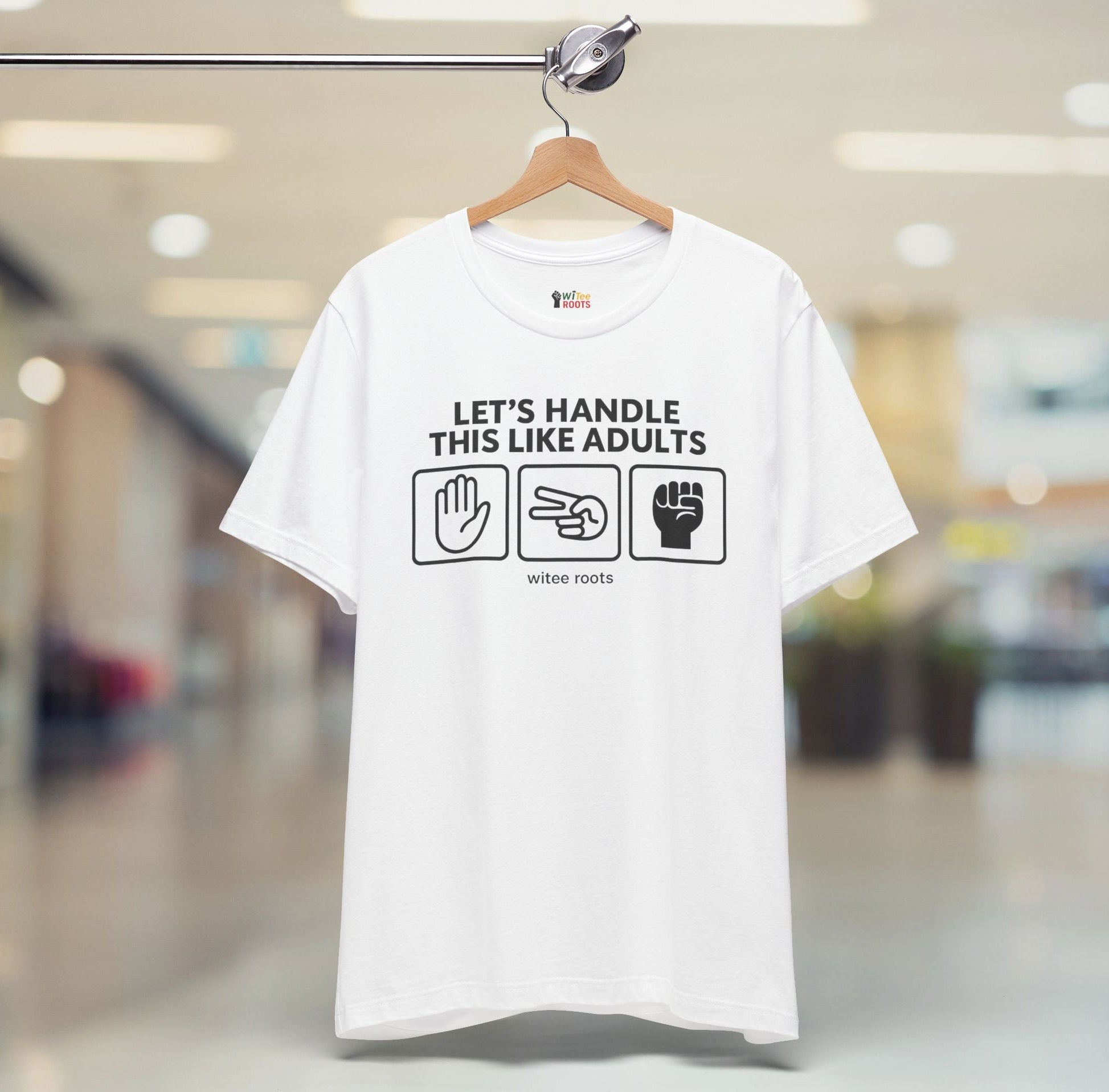 White t-shirt with text and graphics on a hanger in a blurred indoor setting