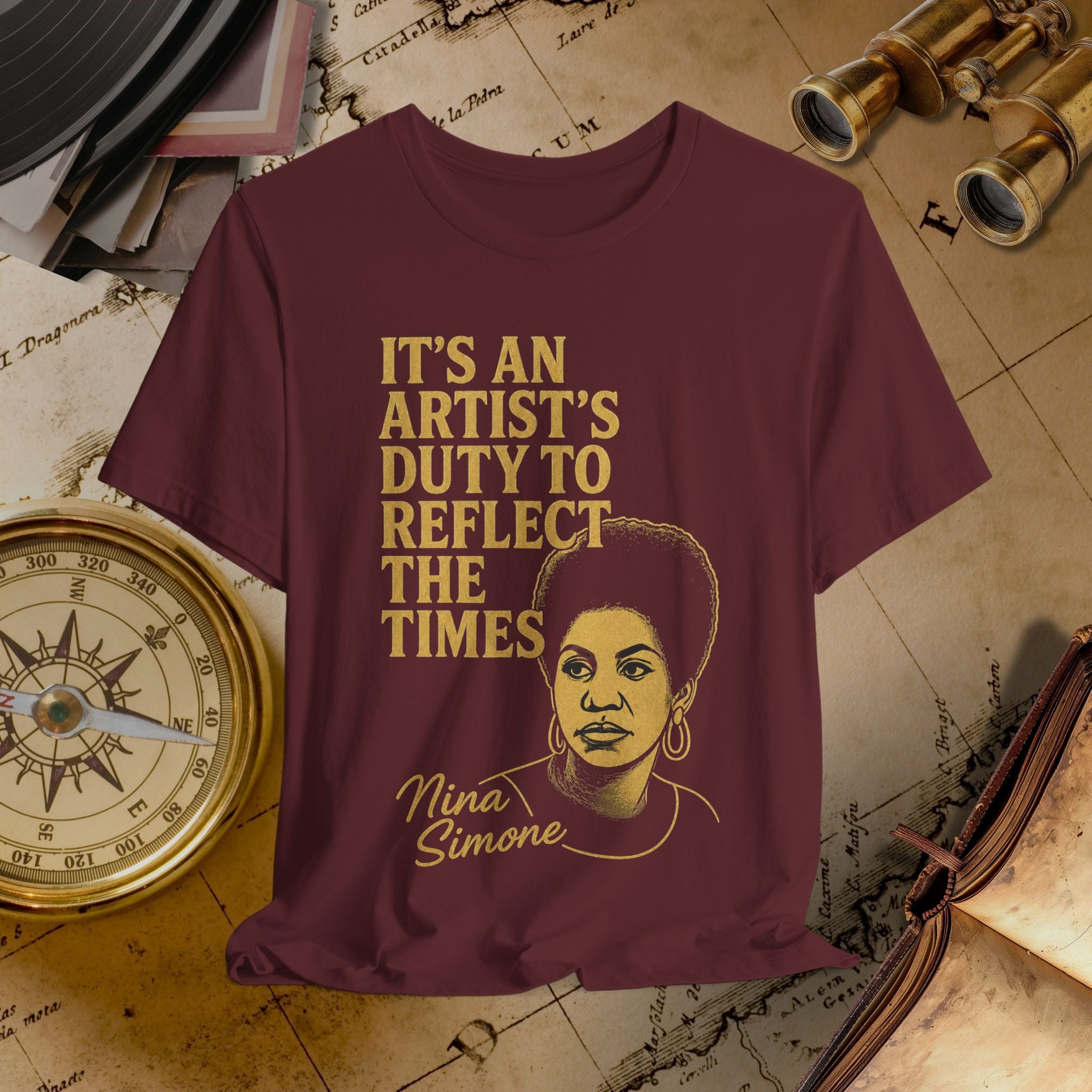 Maroon t-shirt with gold text and illustration of a woman, placed on an old map background. 