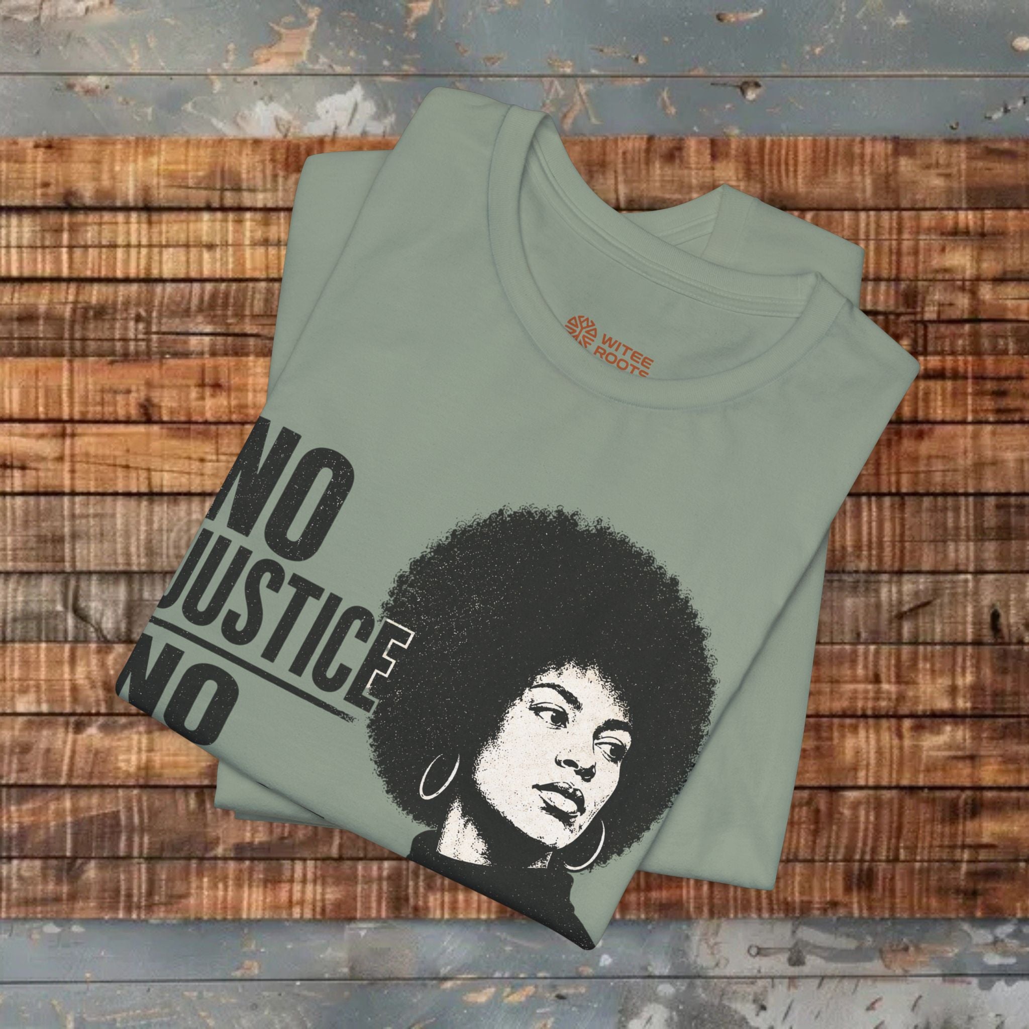 Folded green t-shirt with a graphic and text on a wooden surface