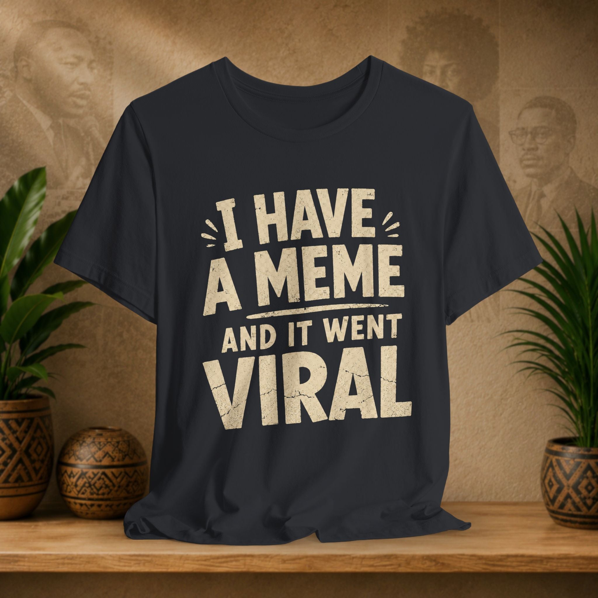 Black t-shirt with 'I have a meme and it went viral' text on a wooden surface with plants and a wall in the background.