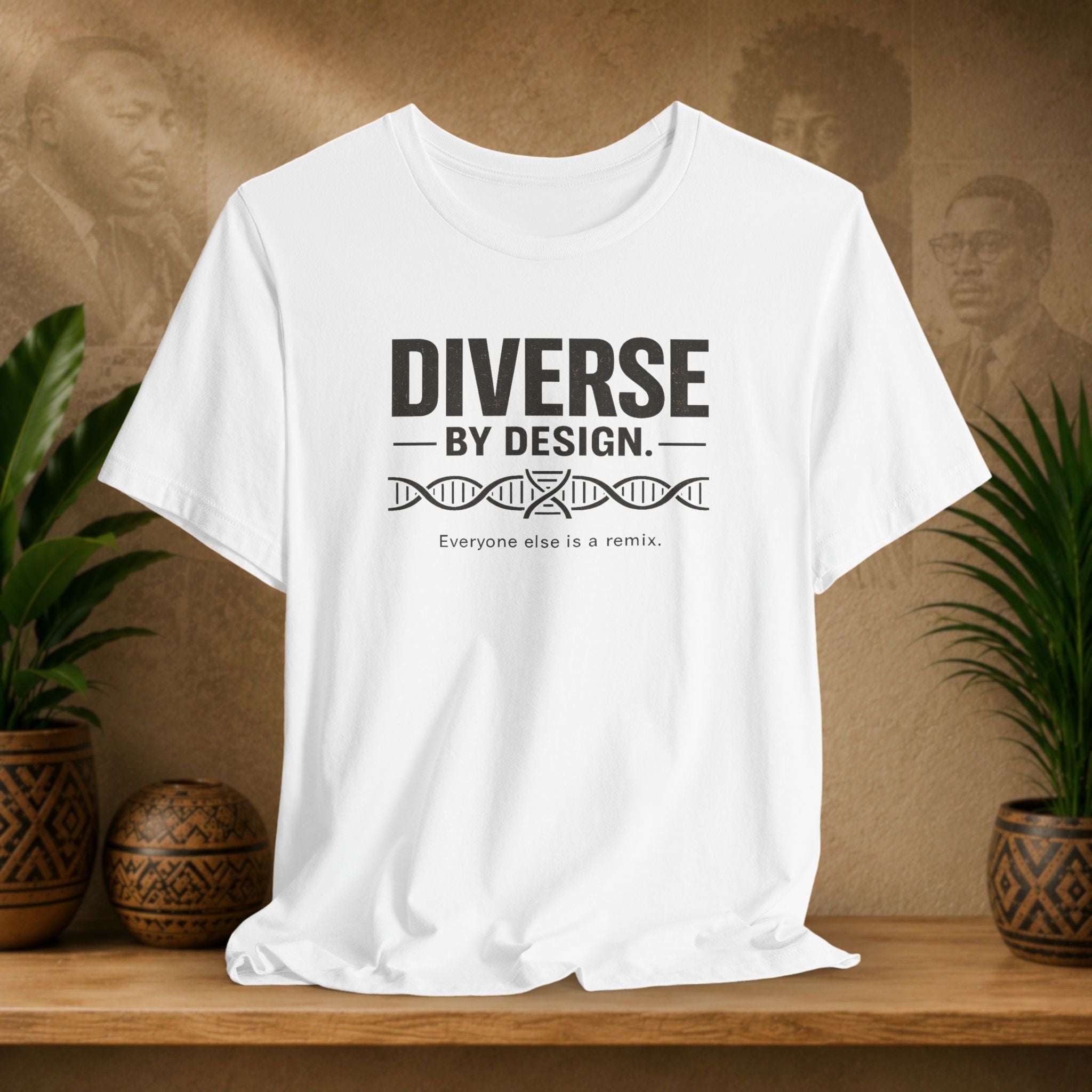 White t-shirt with 'Diverse by Design' text on a wooden surface with plants and a textured wall background