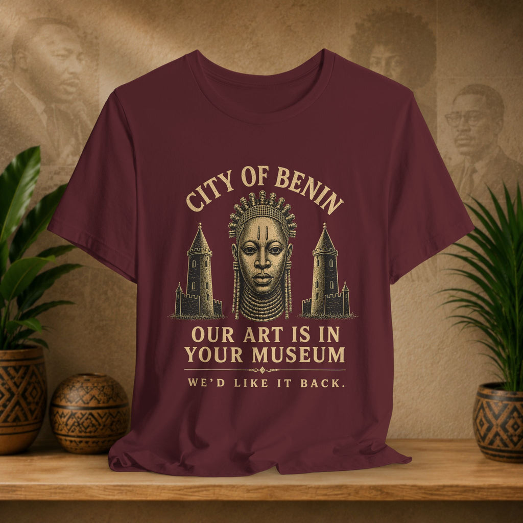 Maroon t-shirt with graphic design and text on a wooden surface with decorative items.