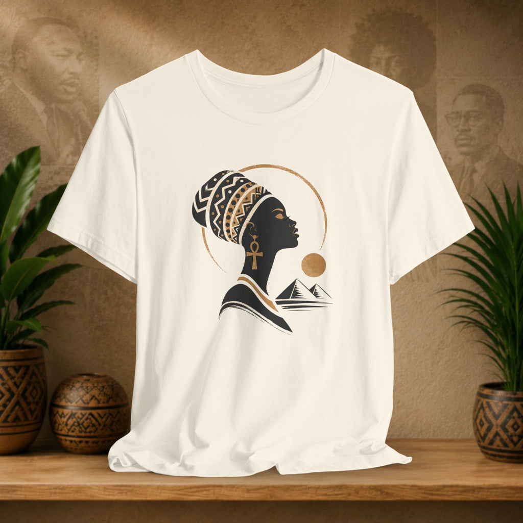 Beige t-shirt with a black silhouette design of a woman with an ankh and mountains on a wooden shelf.