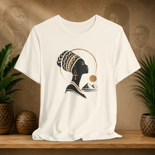Beige t-shirt with a black silhouette design of a woman with an ankh and mountains on a wooden shelf.