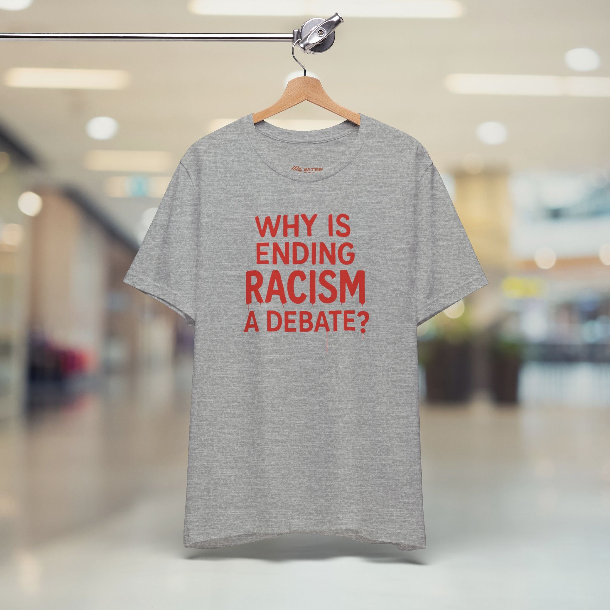 Gray t-shirt with red text on a hanger in a store setting