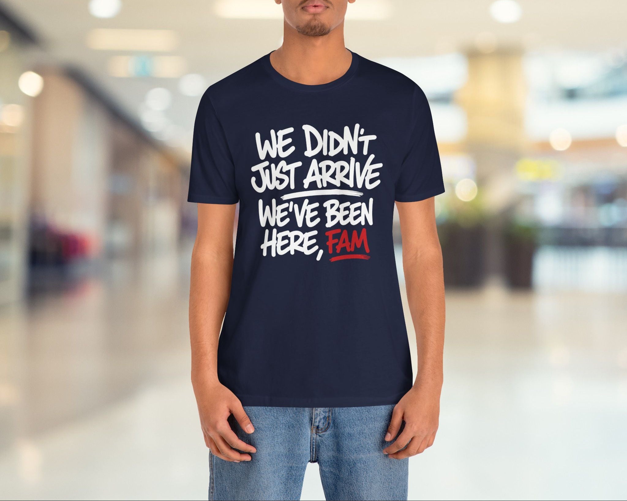 Person wearing a navy blue t-shirt with a humorous message in a blurred indoor setting