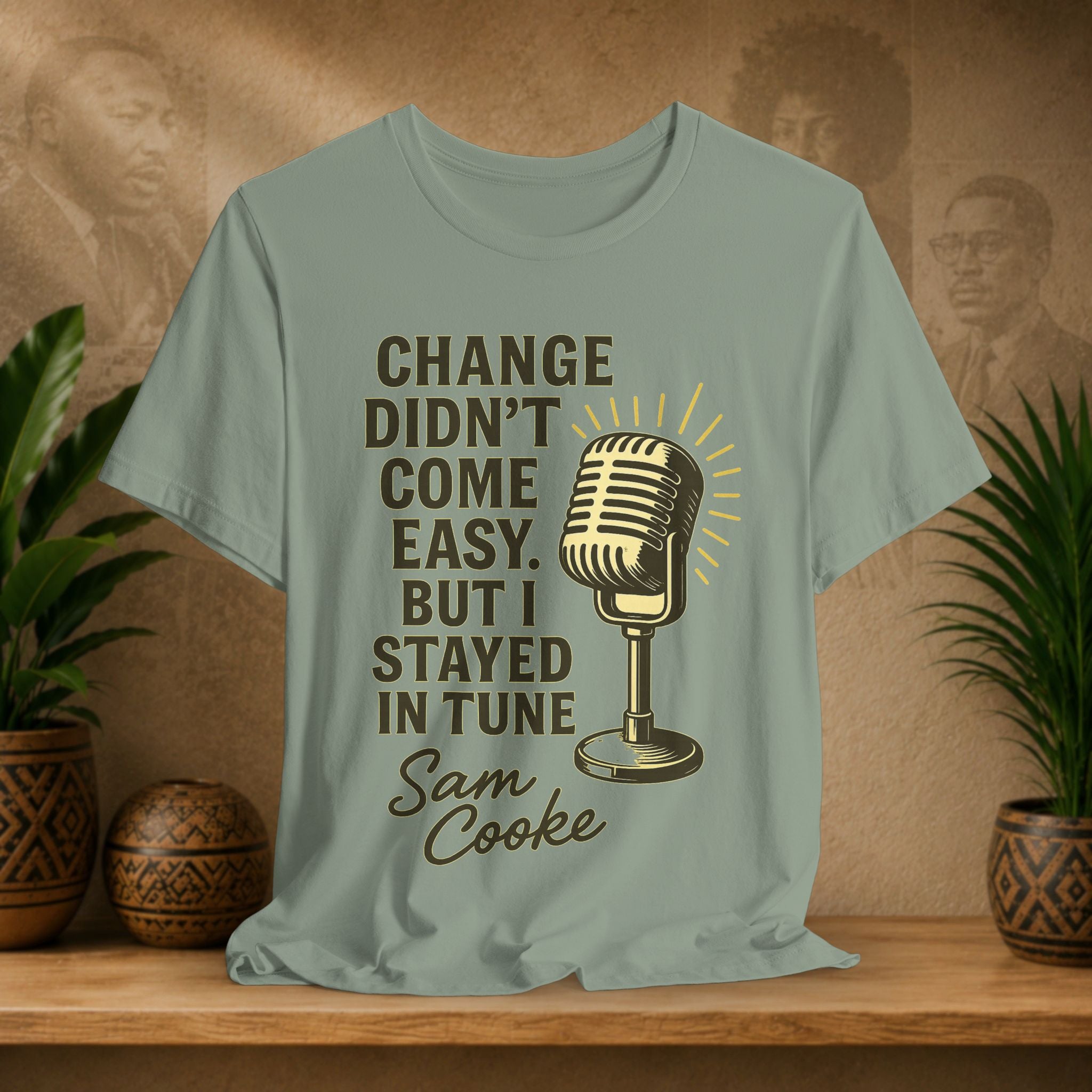 T-shirt with microphone graphic and text on a wooden surface with plants and a blurred background